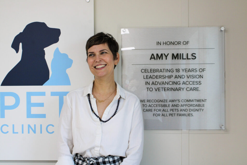 Amy Mills, former CEO of Emancipet, poses in front of the plaque honoring her contribution to Emancipet